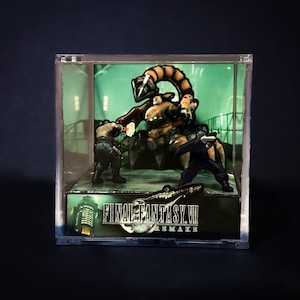 May include: A clear acrylic display case with a diorama of a scene from the Final Fantasy VII Remake video game. The diorama features a large, mechanical scorpion-like creature, two human characters, and a cityscape background. The text "FINAL FANTASY VII REMAKE" is printed on the base of the display case.