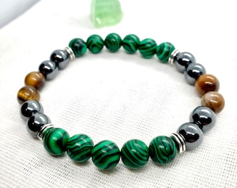 May include: A green, brown, and black beaded bracelet with silver accents. The bracelet is made of malachite, tiger's eye, and hematite beads.