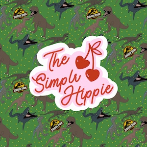 May include: A green background with a pattern of various dinosaurs and the Jurassic Park logo. A pink and white sticker with the text "The Simple Hippie" and cherry illustrations is in the center.