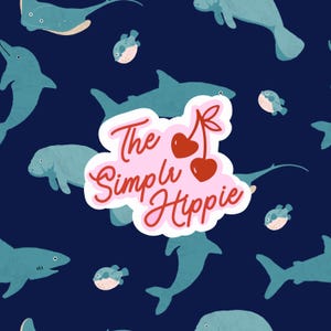 May include: A navy blue pattern featuring various sea creatures, including sharks, dolphins, and pufferfish. The design also includes the text "The Simply Hippie" in a pink and red font, with cherry illustrations.