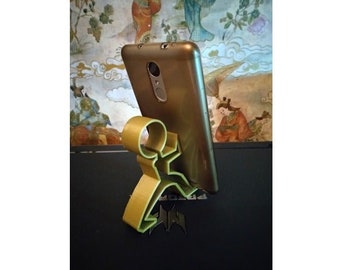 Peut inclure: Un smartphone doré repose sur un support de téléphone jaune et vert. Le support a la forme d'une personne en train de courir. Le téléphone est doré et possède un objectif d'appareil photo à l'arrière.