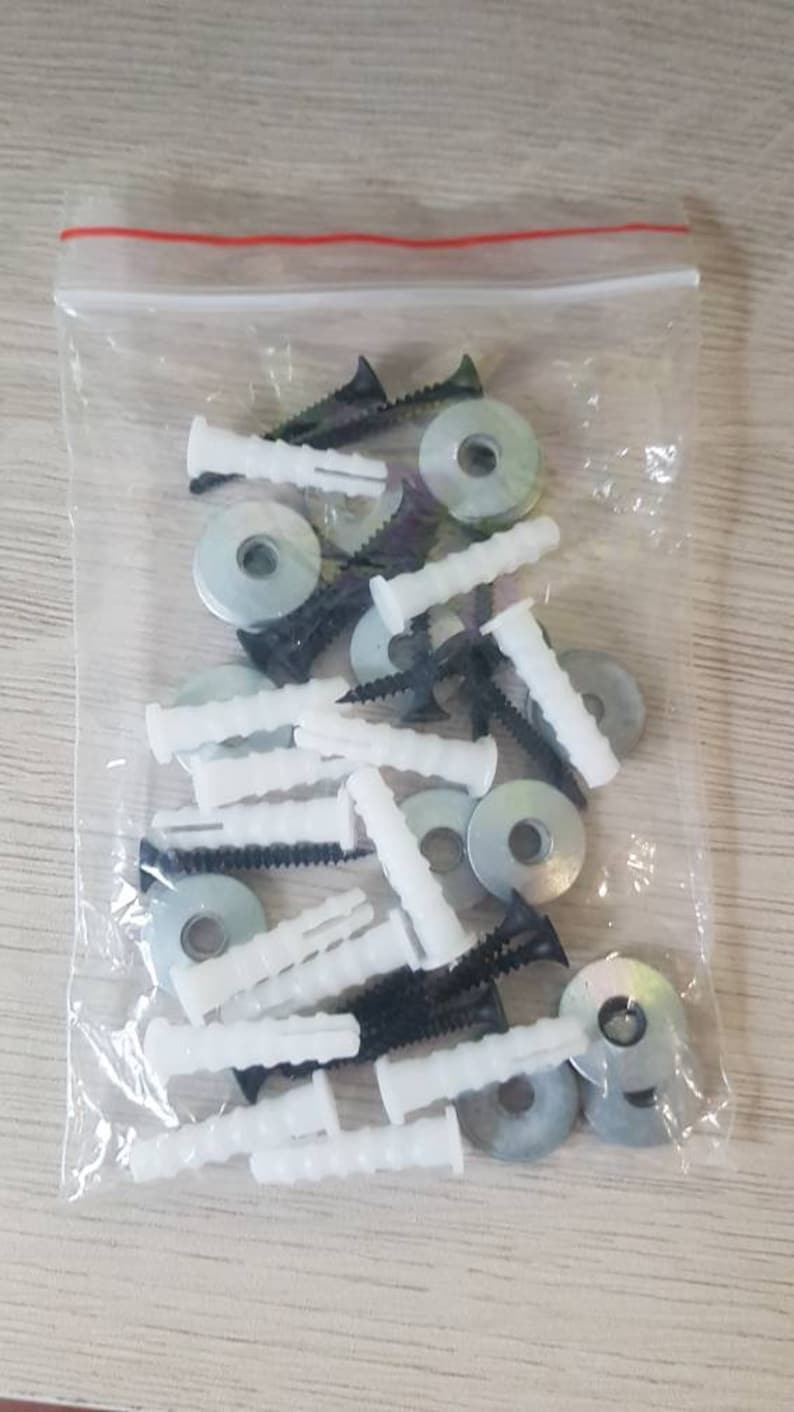 May include: A clear plastic bag filled with white plastic anchors, black screws, and silver metal washers. These are common hardware items used for hanging pictures or other objects on walls.