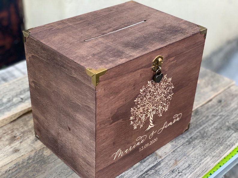 May include: A wooden box with a slot on the top and a lock and key. The box is decorated with a tree design and the text "Marriage of Jared 12.09.2020".