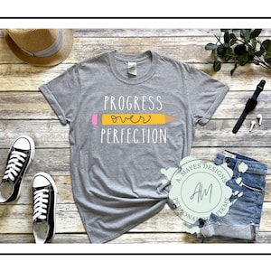 May include: Gray t-shirt with the text "Progress over Perfection" and a yellow pencil with a pink eraser graphic.