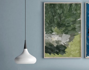 Op de afbeelding: Een grijze bank met een houten basis en een witte hanglamp erboven. Er staat een kleine vaas met witte bloemen op een houten tafel voor de bank. Twee ingelijste abstracte schilderijen hangen aan de muur achter de bank.