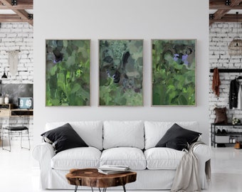 May include: Three abstract art prints with a green and purple color scheme. The prints are framed in a light wood frame and are hanging on a white wall.