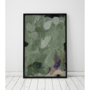 May include: Abstract art print in a black frame. The artwork features a blend of green, white, and black brushstrokes, creating a textured, painterly effect. The piece is displayed against a white wall and a white wooden floor.