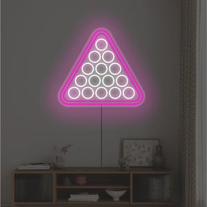 May include: A neon sign depicting a pool rack, with a pink border and white circles representing billiard balls. The sign is mounted on a grey wall above a wooden cabinet.