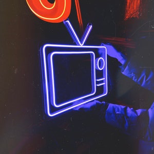 May include: A neon blue sign shaped like a vintage television set with a glowing antenna. The sign is mounted on a dark wall.