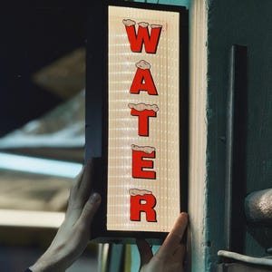 Może przedstawiać: Czarny znak z białym tłem i czerwonymi literami tworzącymi napis "WATER" z chmurą nad każdą literą.