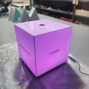 以下が含まれることがあります： ハート型のトップと側面に「@aleksakzm create」というテキストが書かれた紫色の立方体です。