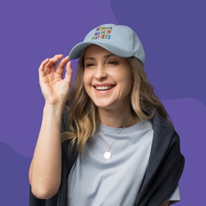 Model wearing a light blue dad hat with Mental Health Matters embroidered in colorful letters.