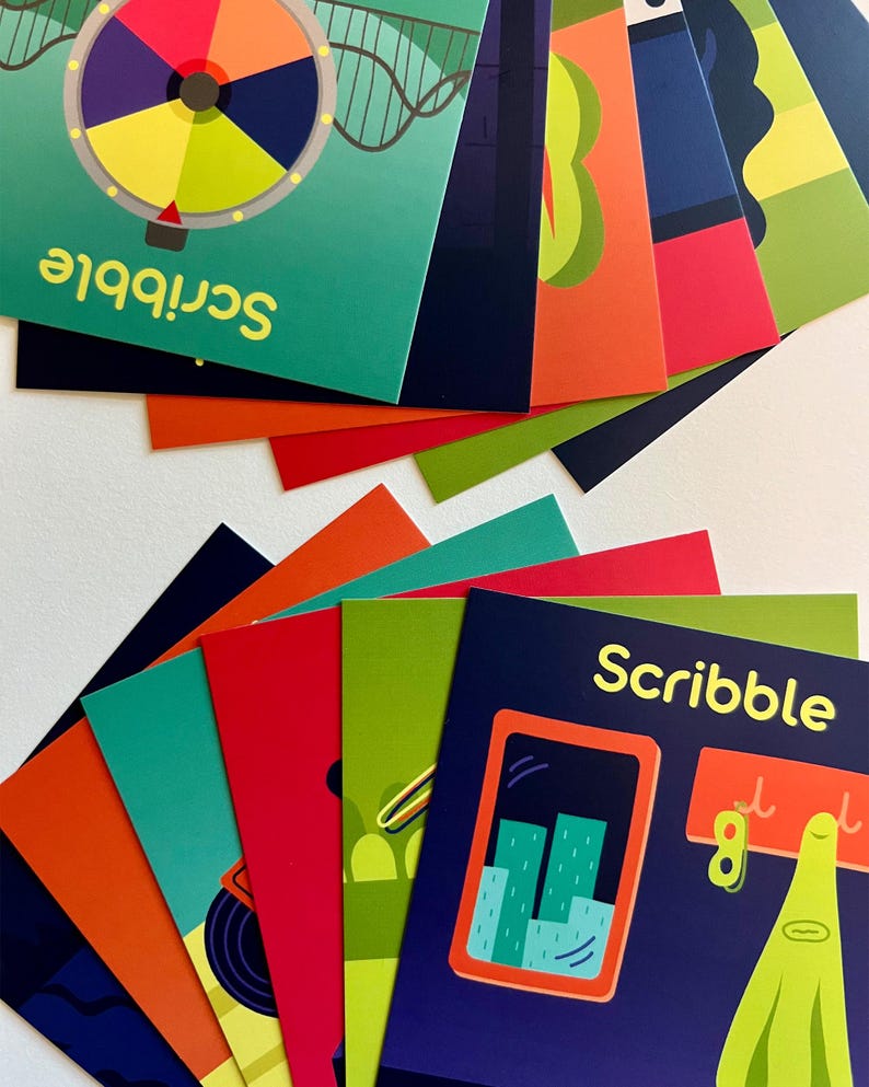 May include: A collection of colorful cards with illustrations and the word "Scribble." The cards feature various designs, including a colorful wheel, a cityscape, and abstract shapes. The cards are fanned out, showcasing their vibrant colors and playful themes.