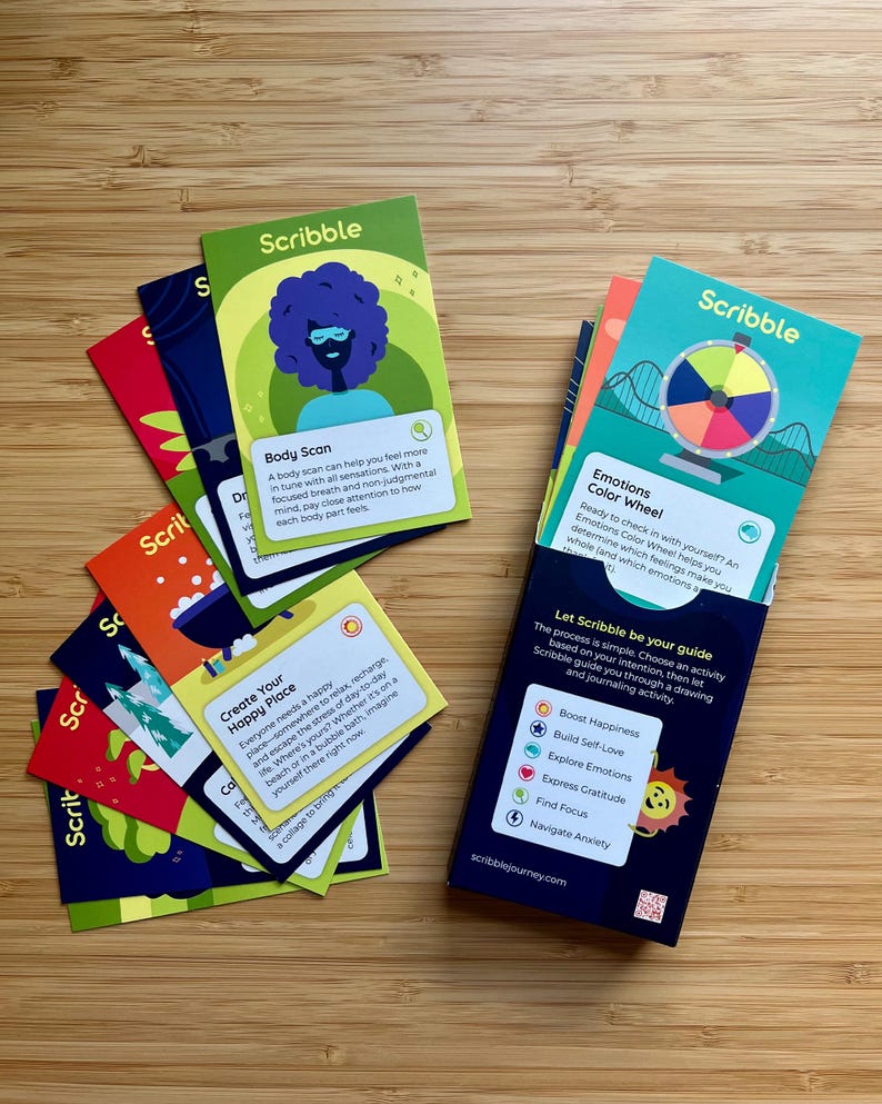 May include: A collection of colorful Scribble cards with illustrations and text, including "Body Scan" and "Emotions Color Wheel." The cards are designed for drawing and journaling activities, with a focus on boosting happiness and exploring emotions.