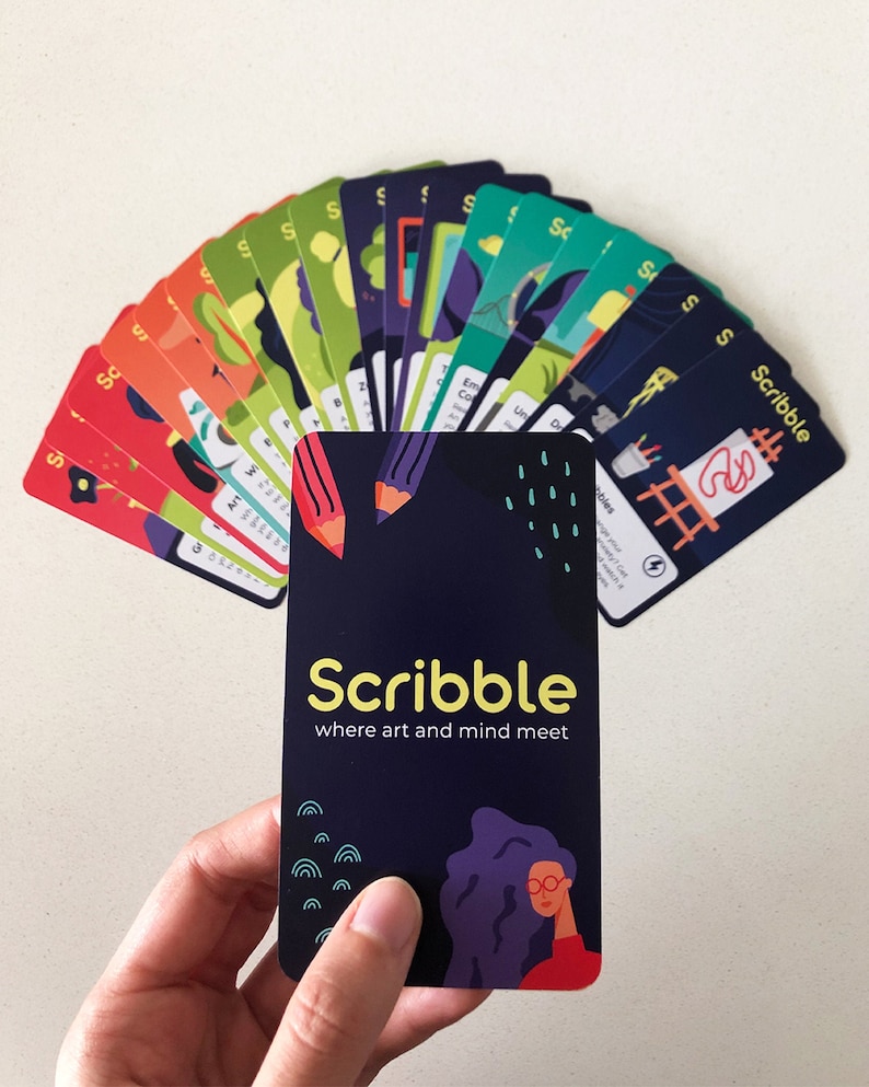 Illustrated card deck displaying drawing and journaling activities for mental health. Hand holding a card with the Scribble logo.