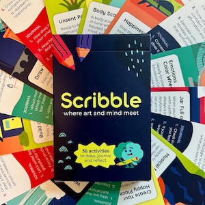 May include: A deck of "Scribble" cards with the tagline "where art and mind meet." The box is navy blue with white and yellow text, and features 36 activities to draw, journal, and reflect. Colorful cards surround the box.