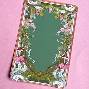 May include: A rectangular card with a green centre and an ornate floral border. The border features pink and white flowers, green leaves, and stylized bottles with mushrooms. The card has a pink background.