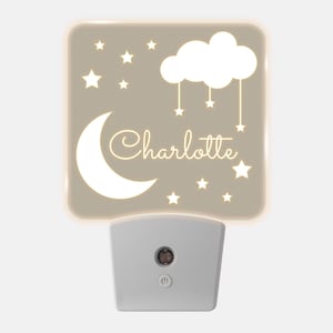 May include: A beige night light with a white crescent moon, a cloud with stars hanging from it, and the name "Charlotte" written in cursive. The night light has a white plug-in base with an on/off switch.