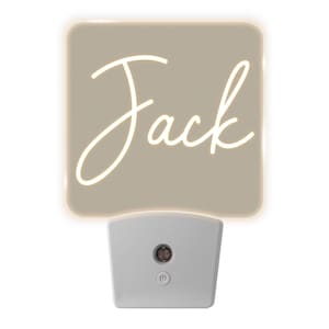 May include: A beige night light with a white power button and the name "Jack" written in white script on the front.