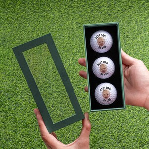 a person holding a box with three golf balls in it