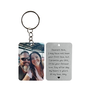 May include: A silver keychain with a photo of a couple on one side and an engraved message on the other side. The message reads: "Dearest Nick, I may have not been your first love, but I promise you this, I'll be your forever love. Day after day my heart is yours. All my love, Amy."