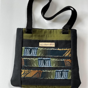 May include: A green and black fabric tote bag with a patchwork design of colorful fabric strips. The bag has a black strap and a small label that reads "KEMNANTANGO".