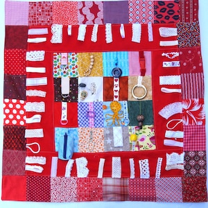 May include: A sensory board in red and various colours, featuring a patchwork design. It includes different fabrics, lace, buttons, and a wooden bead strand. Designed for tactile exploration and sensory play, it offers a variety of textures and objects.