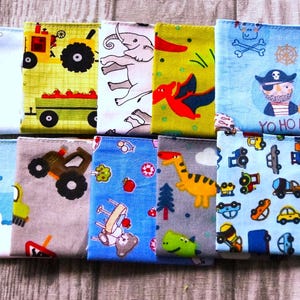 May include: A collection of ten colorful, patterned fabric squares. Designs include a tractor, elephants, dinosaurs, a pirate, and various vehicles. The squares are in shades of blue, yellow, green, and white, suitable for children's crafts or accessories.