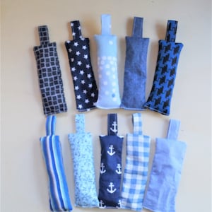 Puede incluir: Un surtido de diez saquitos rectangulares de tela con asas de lazo. Los saquitos presentan varios diseños azules, incluyendo estrellas, lunares, anclas, rayas y cuadros. Los saquitos están diseñados para aromaterapia o fines decorativos.