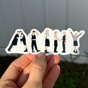 May include: A die-cut vinyl sticker featuring seven stylized figures arranged to form the word ARMY. Each figure is depicted in a unique pose wearing black and white clothing, with distinct hair colors including blue, black, pink, and blonde.