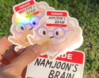 May include: Two holographic stickers and one rectangular sticker featuring a cartoon brain wearing purple glasses and reading a book. The text on the stickers reads INSIDE NAMJOON'S BRAIN and rpwp special program in black and red lettering.