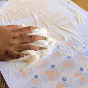 May include: A white sheet of paper with a hand washing guide printed on it. The guide includes 12 steps for washing hands, with illustrations of hands in each step. The paper is covered in white foam.
