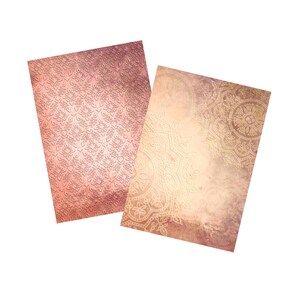 May include: Two decorative paper sheets with different patterns. One sheet has a pink and white damask pattern. The other sheet has a light brown background with a gold mandala pattern.