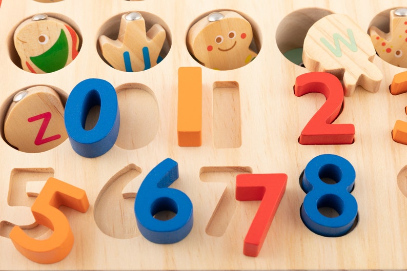 K&ouml;nnte beinhalten: Holz-Lernspielzeug mit bunten Zahlen und Formen. Die Zahlen sind blau, orange und rot. Die Formen umfassen einen Fisch, eine Blume und einen Lebkuchenmann. Entwickelt f&uuml;r fr&uuml;hes Lernen und Zahlenverst&auml;ndnis.