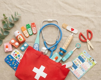 May include: A red first aid kit with a white cross, surrounded by toy medical tools. Includes a stethoscope, thermometer, syringe, bandages, pills, and scissors. The toys are in various colors, including blue, red, orange, and green.