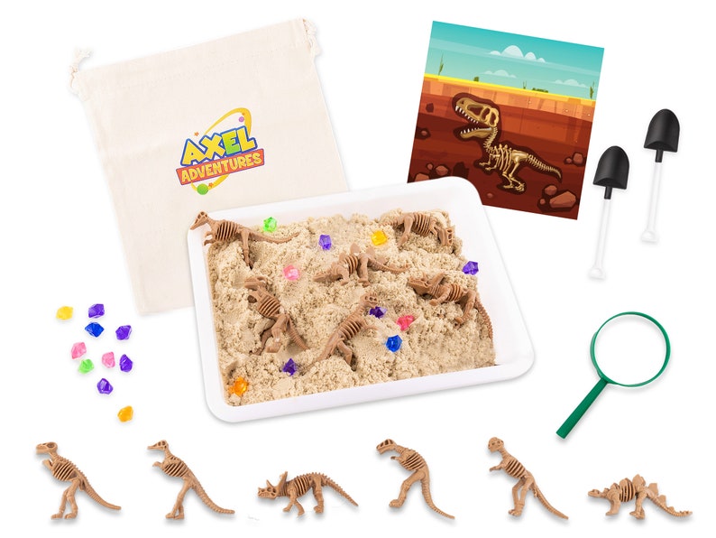 May include: A dinosaur excavation kit with a white tray filled with sand and toy dinosaur skeletons. The kit includes a magnifying glass, small shovels, and a bag with the text "Axel Adventures". Colorful gems are scattered throughout the sand.