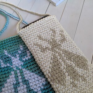 May include: Two crocheted phone cases, one in a teal and white pattern and the other in a beige color. Both cases have a strap.