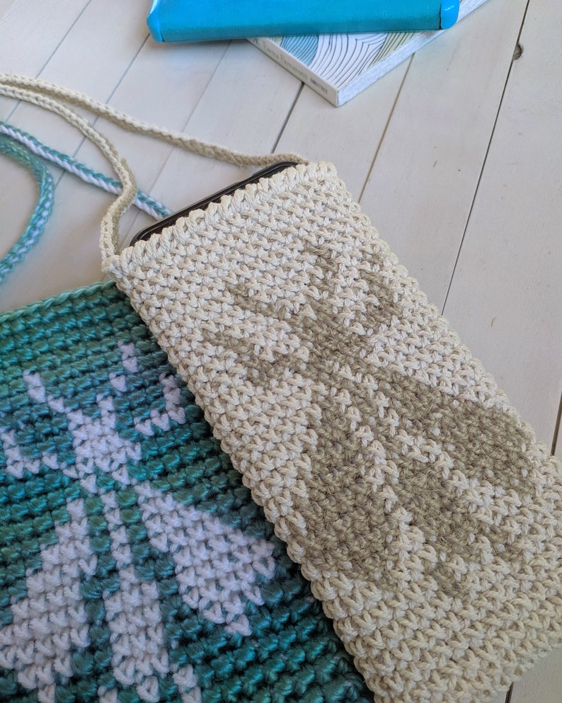 May include: Two crocheted phone cases, one in a teal and white pattern and the other in a beige color. Both cases have a strap.