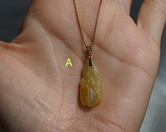 Può includere: Una collana con catena d'oro con un ciondolo in giada gialla intagliato con un motivo floreale.