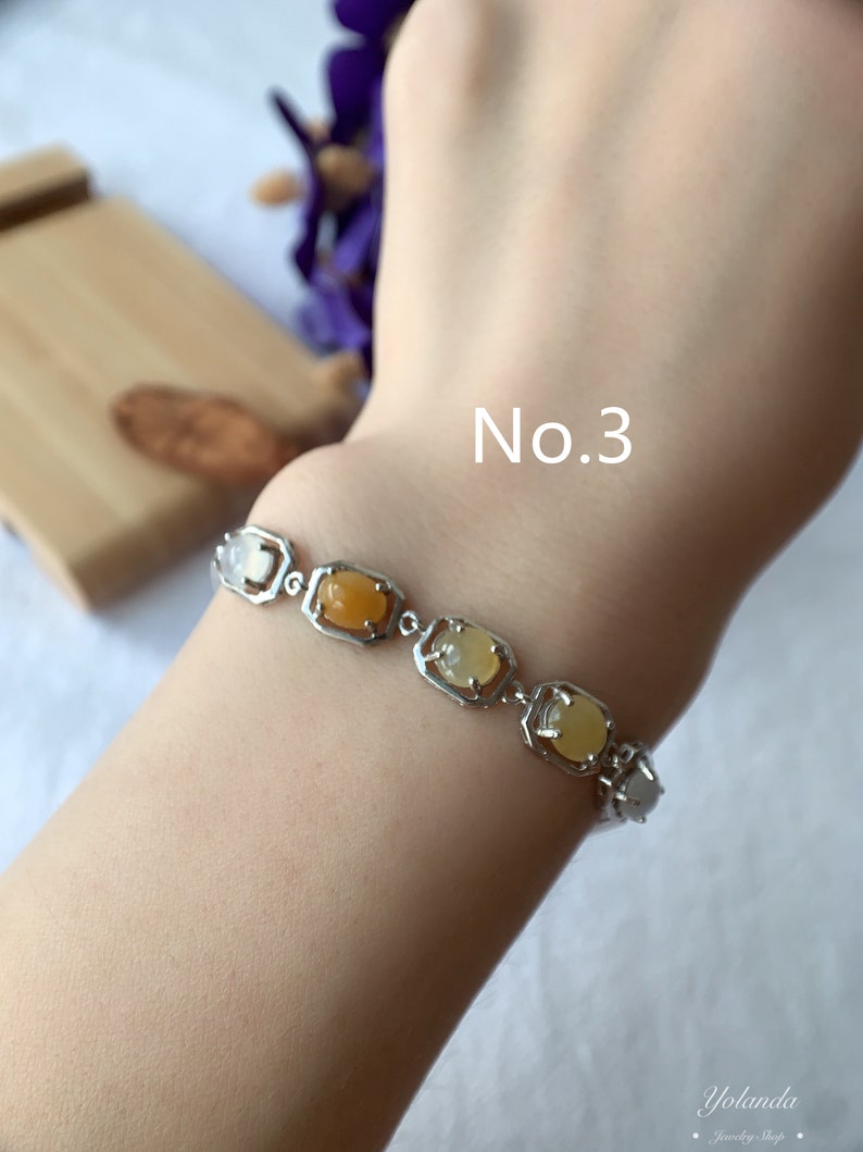 May include: A silver bracelet with a row of oval-shaped gemstones in shades of yellow and orange. The bracelet is on a person's wrist and the text "No. 3" is visible above the bracelet.