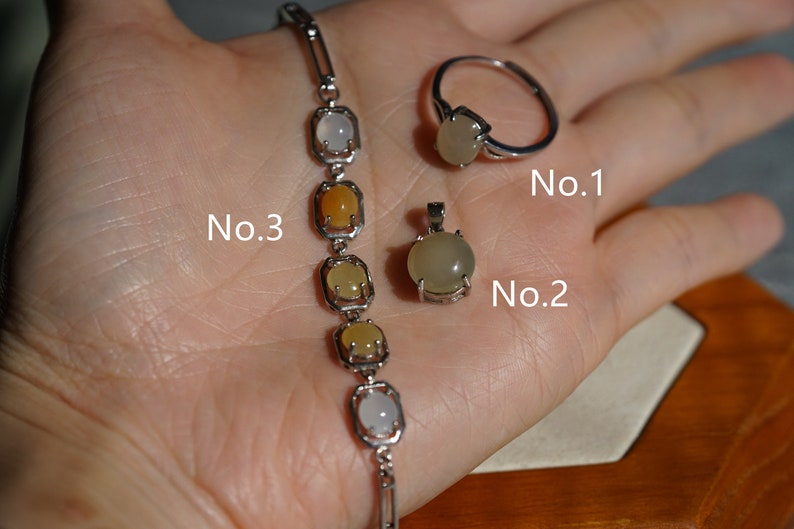 May include: A silver bracelet with five oval-shaped gemstones in shades of white, yellow, and orange.  A silver ring with a white oval-shaped gemstone. A silver pendant with a white oval-shaped gemstone. The items are labeled No. 3, No. 2, and No. 1.