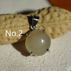 May include: A silver pendant with a round, light gray gemstone set in a silver bezel. The pendant is labeled "No. 2".