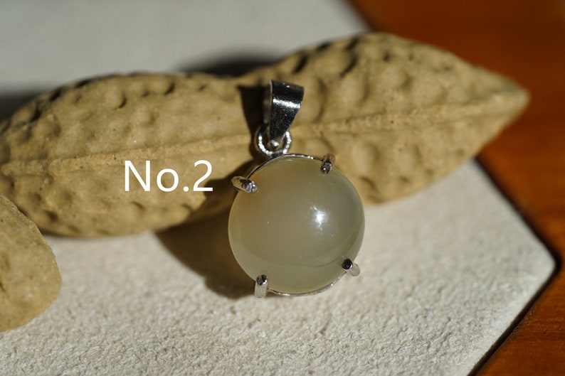 May include: A silver pendant with a round, light gray gemstone set in a silver bezel. The pendant is labeled "No. 2".
