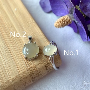 May include: Two silver rings with a light green gemstone. The ring on the left is labeled "No. 2" and the ring on the right is labeled "No. 1".