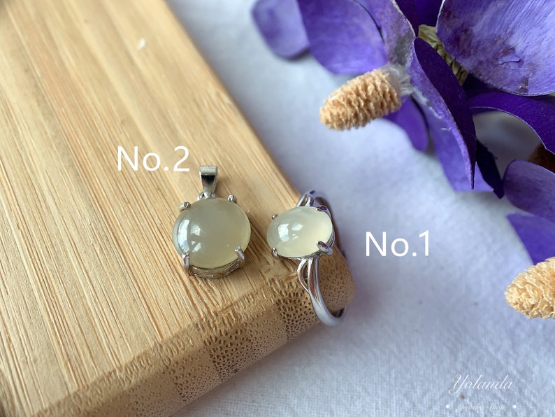 May include: Two silver rings with a light green gemstone. The ring on the left is labeled "No. 2" and the ring on the right is labeled "No. 1".