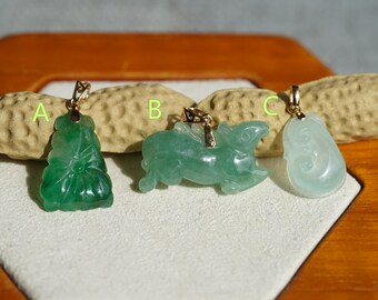 May include: Four jade pendants with gold bail settings. The pendants are carved in the shapes of a flower, a rabbit, a fish, and a dragon. The pendants are displayed on a wooden surface.