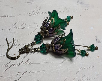 May include: A pair of green glass flower earrings with bronze accents and green crystal beads. The earrings are dangling and have a vintage style.