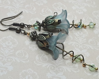 May include: A pair of blue glass flower earrings with antique gold-toned metal accents and green crystal beads. The earrings feature a delicate, twisted wire design.