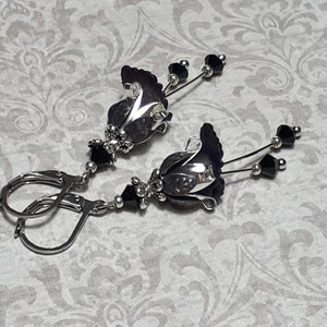 Gothic black vintage fairy flower earrings, delicate fluted flowers have been been paired with antique silver filigree floral bead caps. Jet black crystals are added to crystal drops that sway as the earrings move. Finished with lever back hooks.
