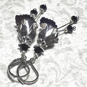 Gothic black vintage fairy flower earrings, delicate fluted flowers have been been paired with antique silver filigree floral bead caps. Jet black crystals are added to crystal drops that sway as the earrings move. Finished with lever back hooks.